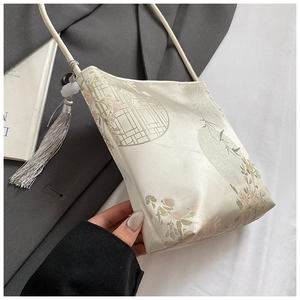 Close-up of beige silk shoulder bag with floral embroidery and jade tassel detail