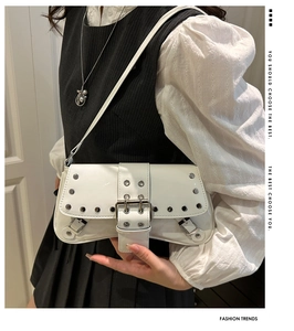 Detail of white glossy shoulder bag featuring silver rivets and large double buckle hardware