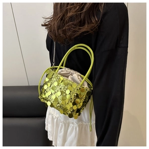 Detail of a bright green sequin bucket bag with drawstring closure and metal chain strap
