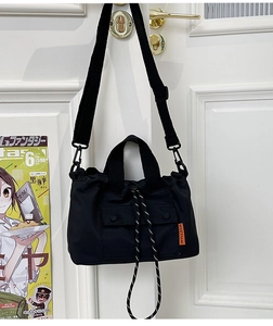 Détail du sac cabas en nylon noir avec fermeture à cordon et bandoulière réglable
