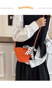 Detail of orange woven bucket bag with large polka dot bow and pearl button accent