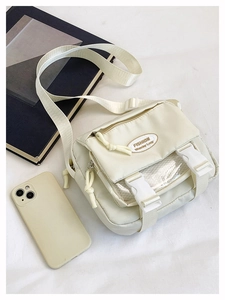 Close-up of beige nylon crossbody bag with dual buckles and front mesh zipper pocket