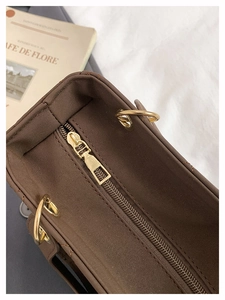 Detailed close-up of dark brown quilted crossbody bag with golden metal hardware