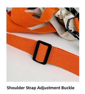 Détail de la bandoulière orange tissée réglable avec boucle noire mate sur un sac cabas
