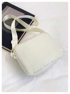 Detail of white puffer crossbody bag with soft quilted texture and nylon strap