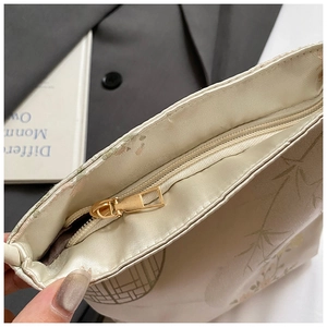 Detail of white fabric bucket bag with elegant bamboo print and gold zipper