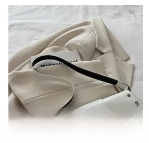 Detail of white patent leather underarm bag featuring silver studs and metal belt buckle