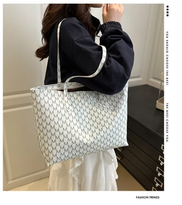 Detail view of large tote bag with M-letter print and long shoulder strap on model