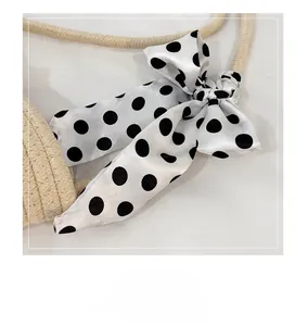 Detail of hand-woven shoulder bag handle decorated with a black and white polka dot silk scarf
