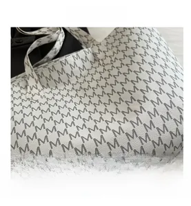 Close-up of pebble leather texture and luxury M-pattern print on large tote bag