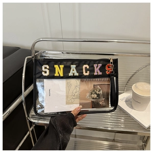 Detail of transparent PVC bag featuring colorful SNACKS chenille embroidery and black trim