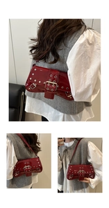 Close-up of red patent leather shoulder bag with silver punk rivets and belt buckles