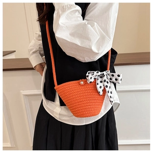 Detail of bright orange woven crossbody bag with polka dot scarf and pearl buckle