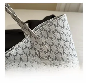 Close-up of leather texture and monogram letter print detail on large tote handbag