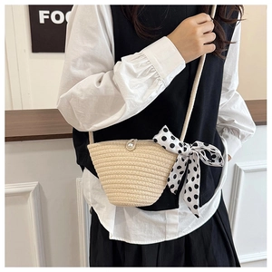 Close-up of beige straw bucket bag with pearl clasp and polka dot scarf detail