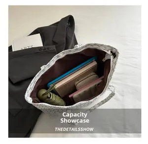 Capacity display of white tote bag with M print showing interior space for laptop and books