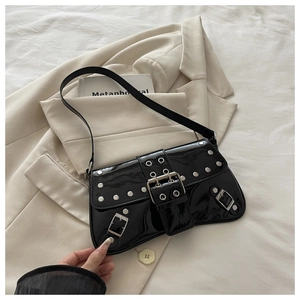 Detail of punk style black patent leather shoulder bag with silver rivets and metal buckle