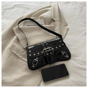Close-up of black patent leather shoulder bag with silver rivets and buckle straps