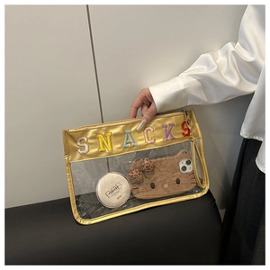 Close-up of a hand holding a transparent PVC makeup bag with snacks letter embroidery
