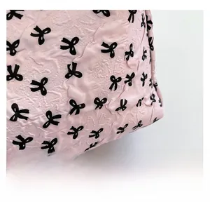 Détail du tissu matelassé rose avec nœuds noirs et texture douce pour sac fourre-tout