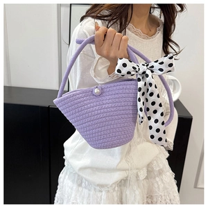 Close-up of purple woven bucket bag featuring a pearl clasp and polka dot silk scarf detail