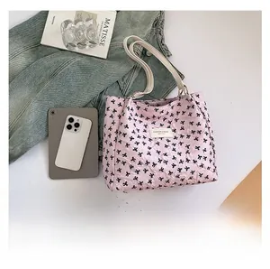 Sac fourre-tout rose avec motifs de nœuds noirs et bandoulières blanches avec accessoires