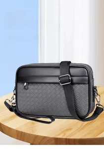 Detalle de la textura tejida gris y costuras de cuero negro en el bolso de hombro para hombre