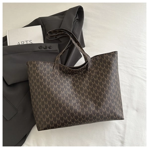 Macro detail of brown tote bag with M-letter monogram print on a suit jacket