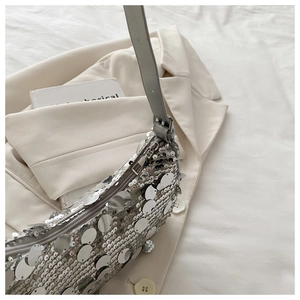 Detailed view of large silver mirror sequins on stylish shoulder bag with metal zipper