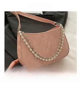 Close-up of pink quilted leather shoulder bag with bow embroidery and pearl chain
