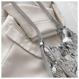 Macro shot of silver sequins on an underarm bag draped over an ivory blazer