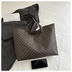 Flat lay of vintage dark brown tote bag with all-over M letter print and daily essentials