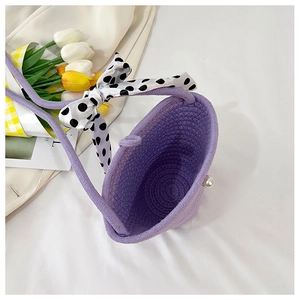Detail of lavender woven handbag with pearl clasp and polka dot bow accessory