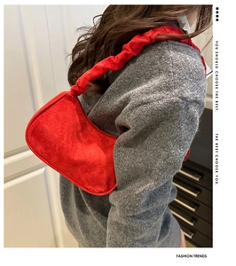 Détail du sac bandoulière en daim rouge avec bandoulière froncée et forme demi-lune