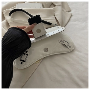 Detail of white patent leather crescent bag with silver studs and magnetic buckle