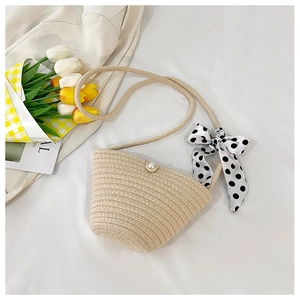 Detail of beige woven straw shoulder bag featuring pearl clasp and polka dot bow accent