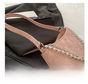 Detail of pink quilted patent leather bag with pearl and silver metal chain strap