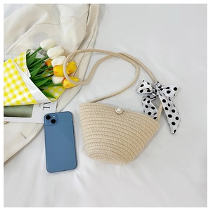 Detail of woven straw bag with pearl button closure and a black polka dot silk scarf