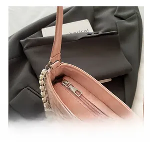Detailed close-up of pink quilted shoulder bag with silver zipper and pearl chain detail
