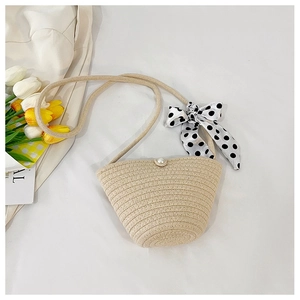 Detail of beige woven crossbody bag with pearl clasp and black white polka dot silk scarf