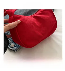 Gros plan détaillé du sac croissant en daim rouge avec fermeture éclair et large anse