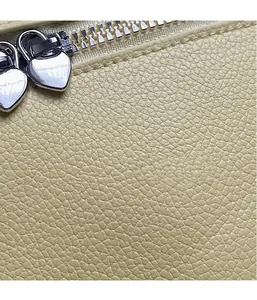 Detail of light yellow pebble grain leather bag featuring silver double heart zippers