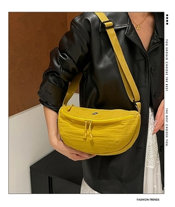 Detail shot of a bright yellow nylon crescent chest bag with double zippers and round logo