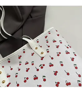 Detail of lychee texture white tote bag with red cherry print and gold rivets