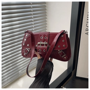 Close-up of wine red patent leather shoulder bag with silver rivets and buckle detail