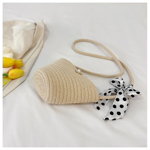 Detail of straw woven bucket bag with pearl closure and polka dot silk ribbon