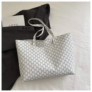 Detail of white tote bag with grey M letter print shown on black blazer background