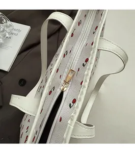 Close-up of smooth gold zipper closure on white tote bag with red cherry print pattern