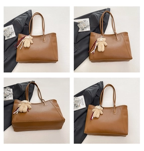 Detail view of large dark brown leather tote bag with plush bear charm and ribbon
