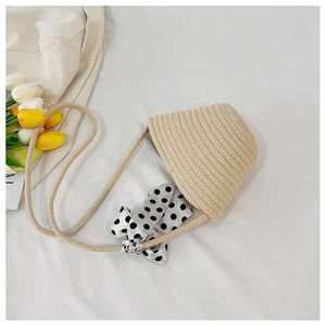 Detailed top view of beige straw handbag with black and white polka dot satin bow accent